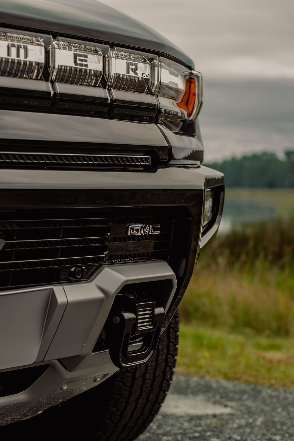 Low angle shot of a GMC truck's front fascia highlighting the aggressive grille and fog light design.