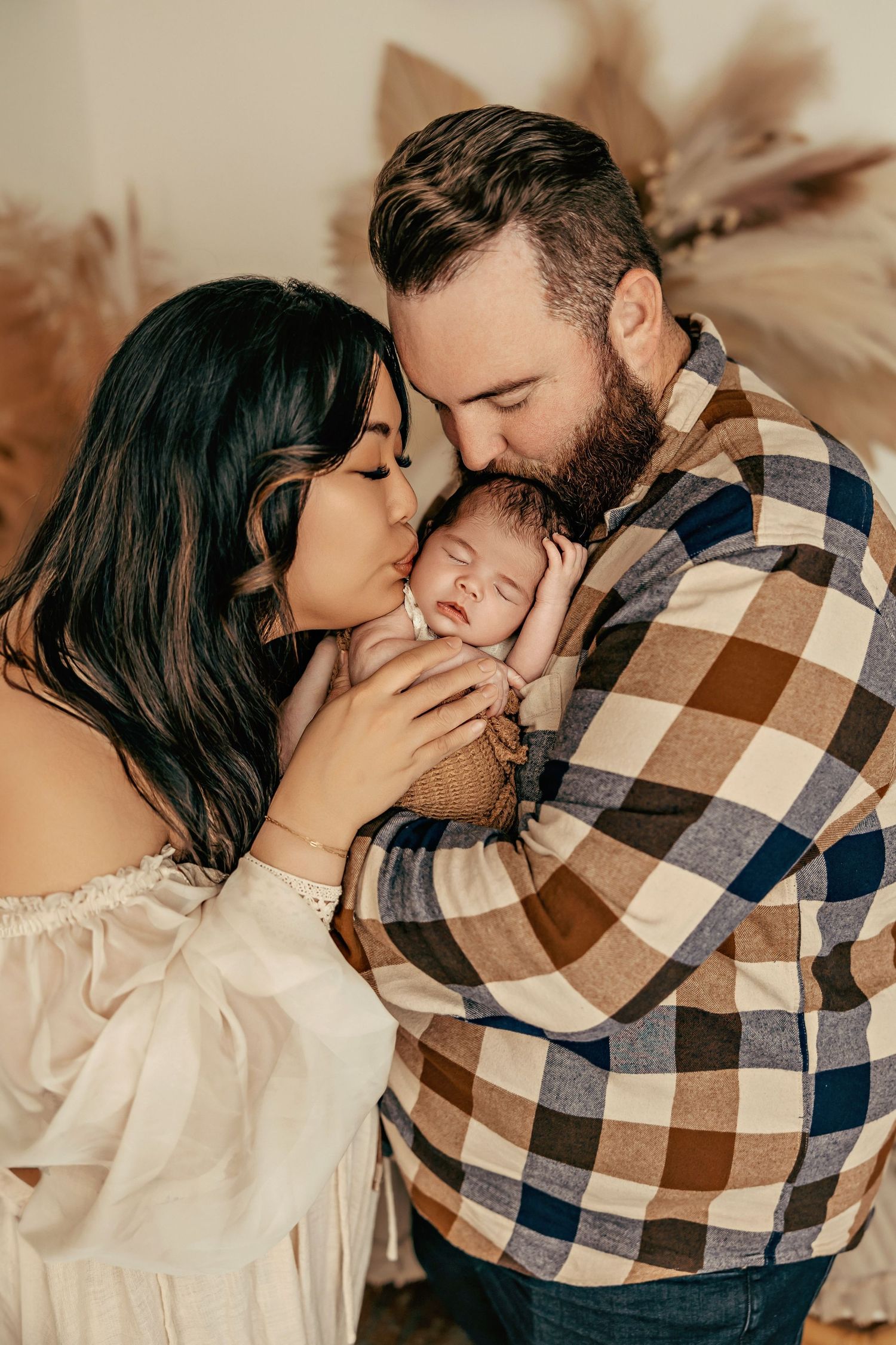 A maternity photo featuring a flowing beige dress against a backdrop of open books and floral arrangements in a dreamy setting.