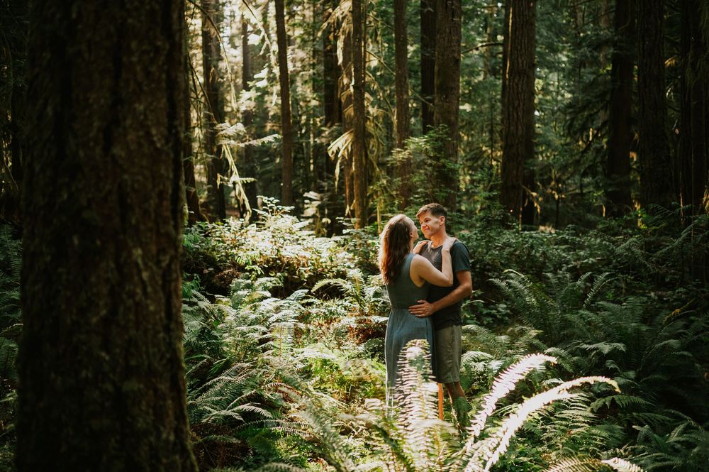 Adventurous couple photographer photoshoot of couple in Cumberland Forest Vancouver Island engagement session hugging in ferns