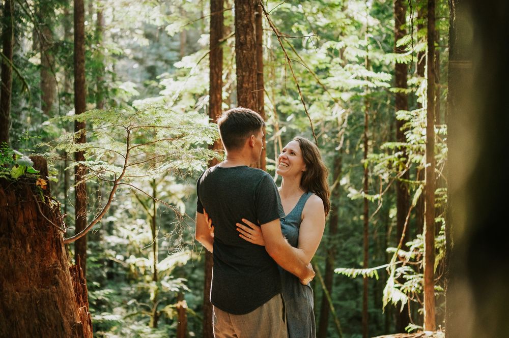 Adventurous couple photographer photoshoot of couple in Cumberland Forest Vancouver Island engagement session smiling holding each other