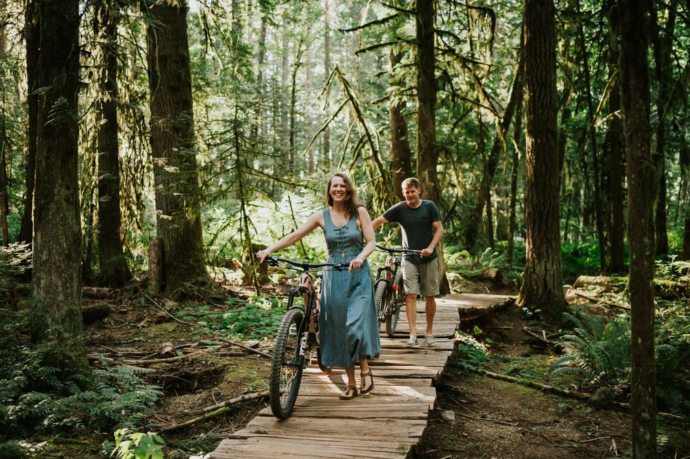 Adventurous couple photographer mountain biking on boardwalk Cumberland Forest Vancouver Island engagement session walking bikes