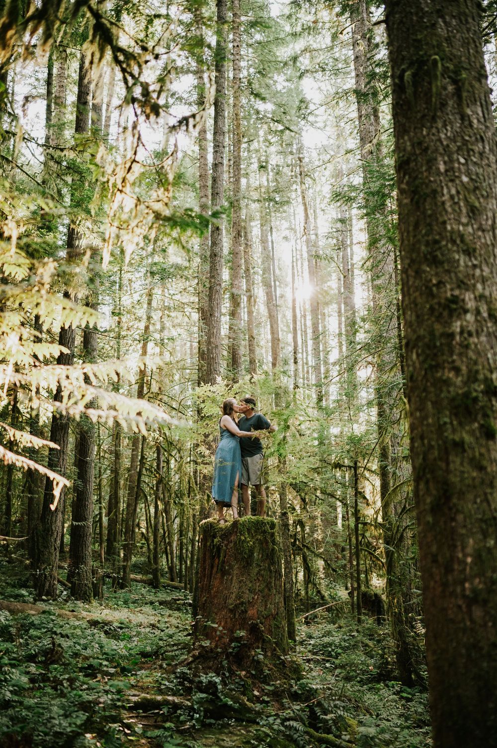 Adventurous couple engagement session photographer photoshoot of couple in Cumberland Forest Vancouver Island standing on tree stump