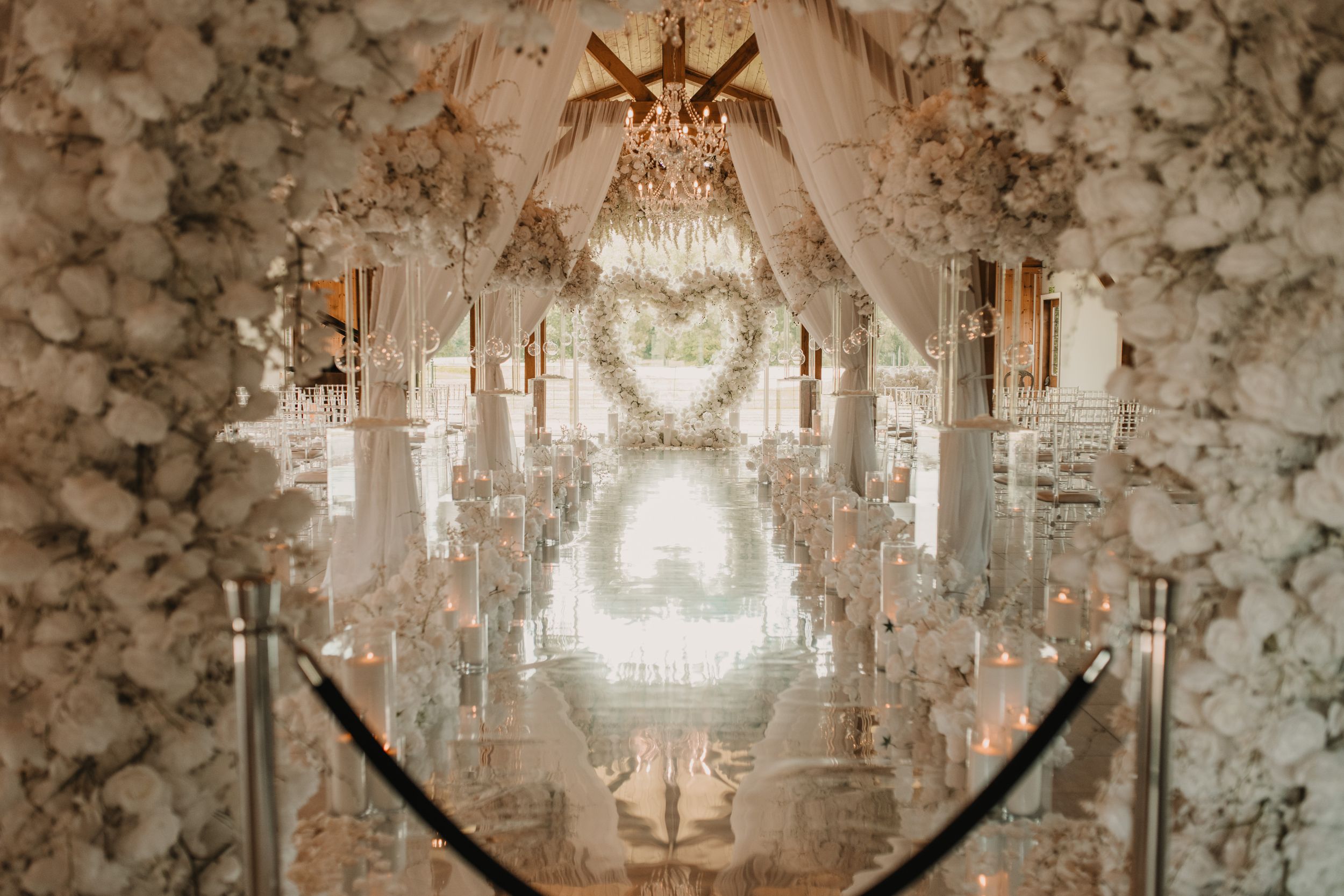 A grand wedding ceremony room with crystal chandeliers and ornate decor features elegant floral arrangements and luxurious table settings