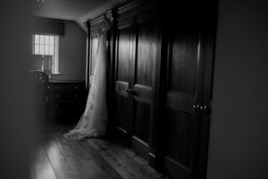 Dark and moody black and white hallway with wooden paneling and dramatic shadows creates an eerie atmosphere at Merrydale Manor