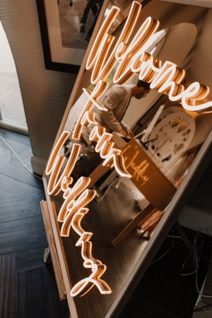Close-up view of glowing orange neon sign letters mounted on a white wall creating an artistic lighting effect at Merrydale Manor