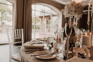 Elegant table settings with glassware and place settings in a sunlit rustic dining room.