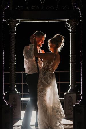Dramatic silhouettes of a newlywed couple dancing in a dark venue with dramatic backlighting and window frames at Merrydale Manor