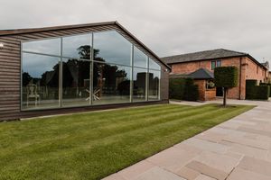 Modern school building exterior with glass windows and walkways surrounded by well-maintained green lawns and landscaping at Merrydale Manor