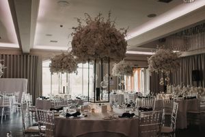 Panoramic view of an elegant wedding reception venue with white chiavari chairs and floral centerpieces.
