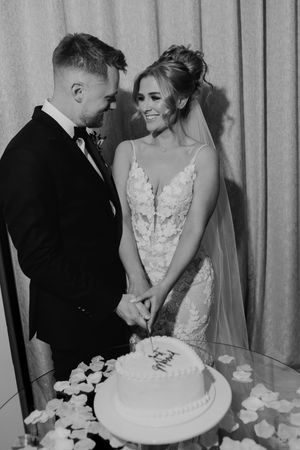 Newlywed couple in black and white share intimate moments while cutting their wedding cake together at Merrydale Manor