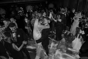 A couple shares their first dance as newlyweds on a dimly lit dance floor surrounded by wedding guests at Merrydale Manor