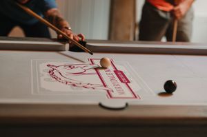 Close-up view of hands using red ink and chopsticks to create traditional Chinese calligraphy on white paper.