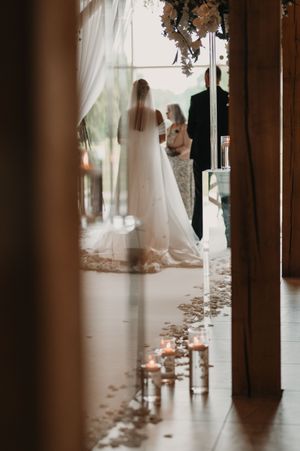 A romantic wedding ceremony scene with candlelit aisle and flowing white curtains creating a dreamy atmosphere.