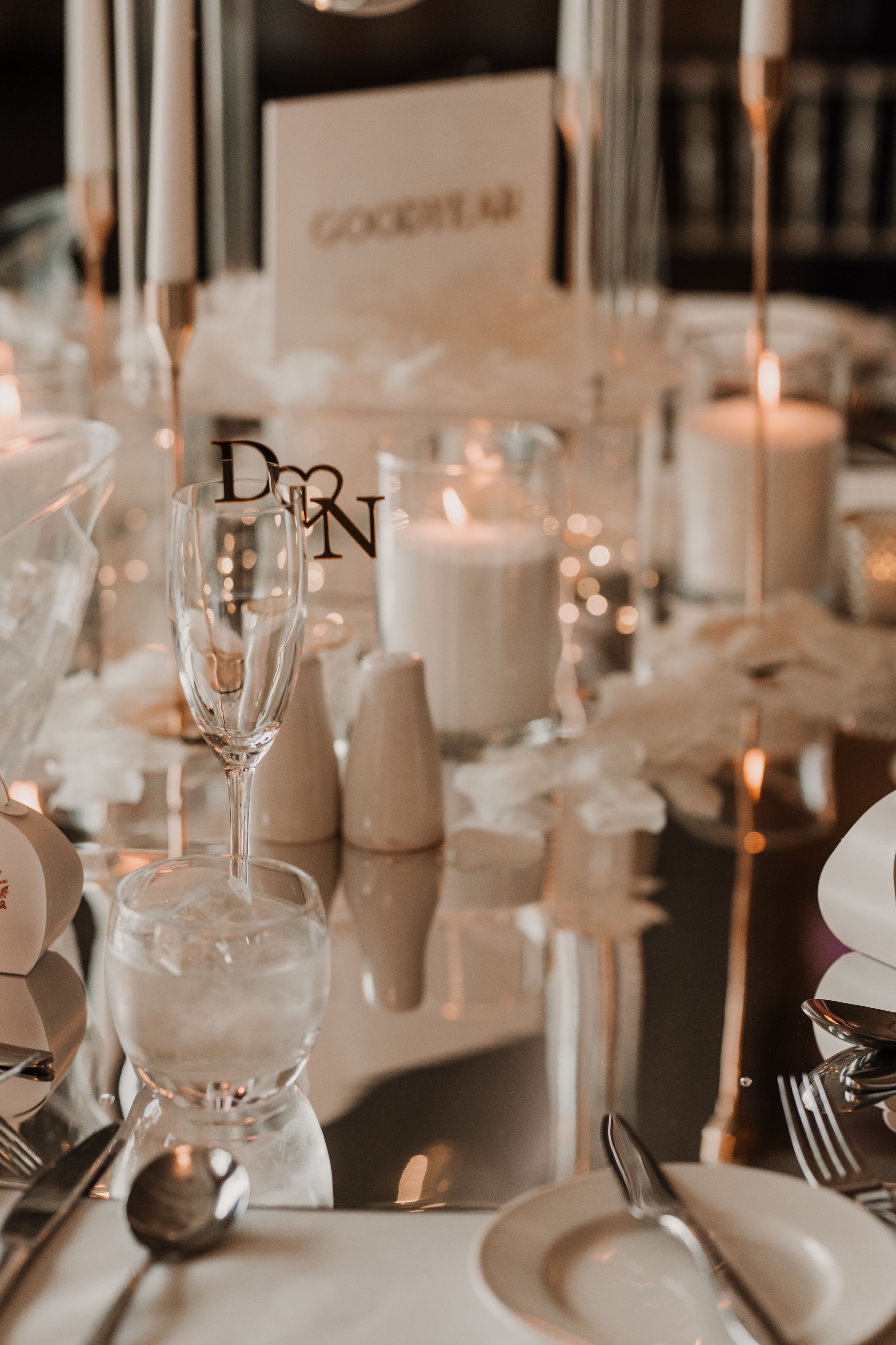 Elegant wedding reception table setting with white candles, crystal glasses and soft romantic lighting at Merrydale Manor