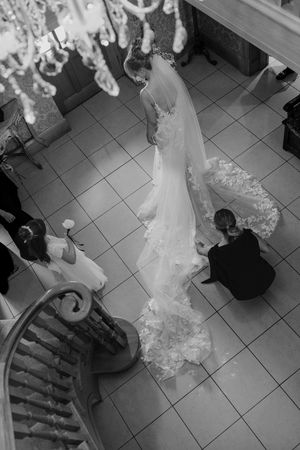 A bride in a flowing white wedding dress walks across a tiled floor in a sequence of black and white photographs.