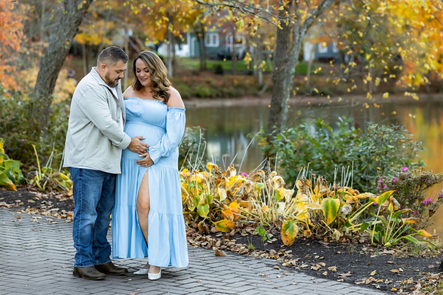 Romantic couple in dress and denim share tender moments in a vibrant autumn garden setting with golden leaves Maternity photographer rva