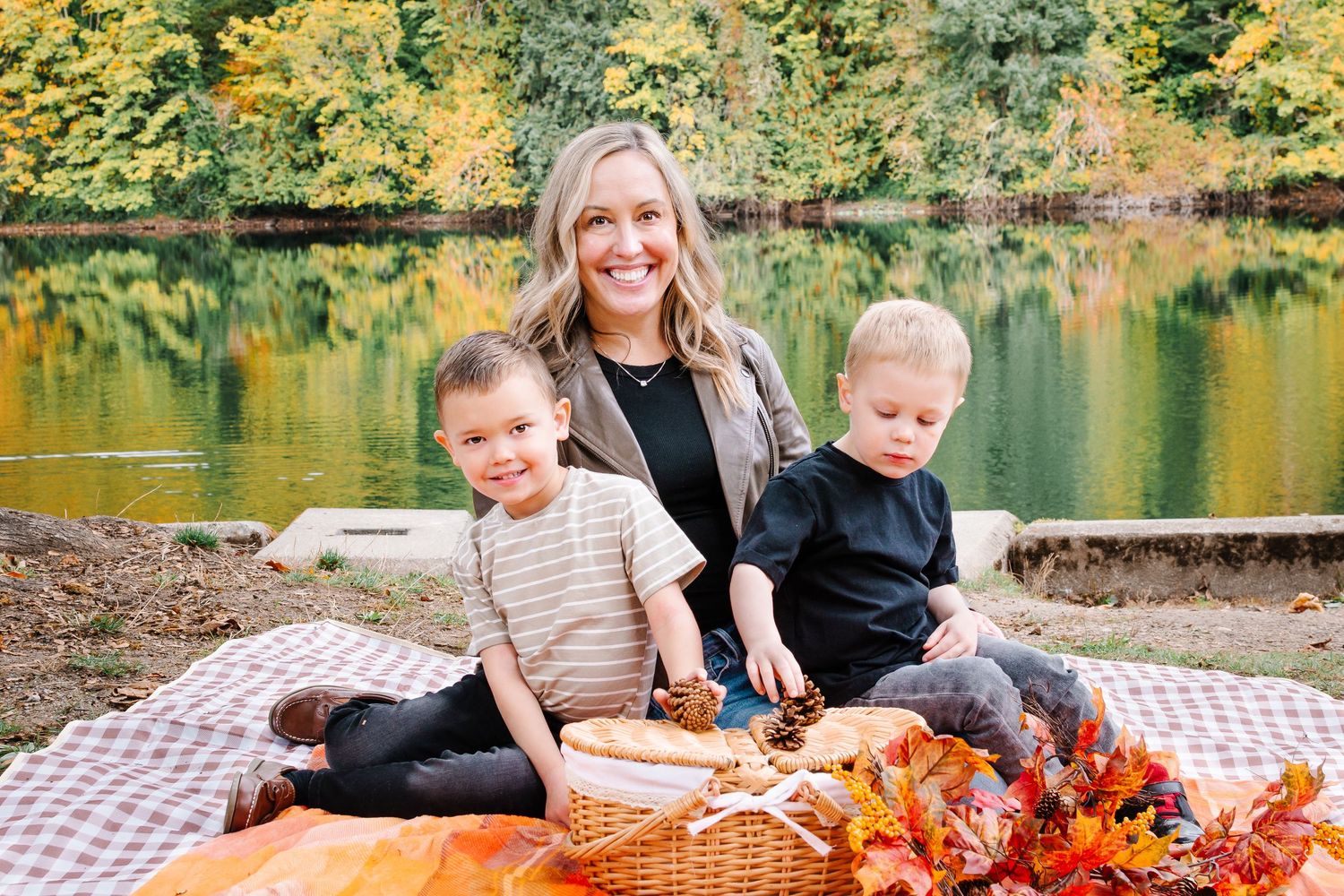 Family of mother and sons sitting by the lake during fall golden hour at Lake Fenwick Park in Kent, Washington