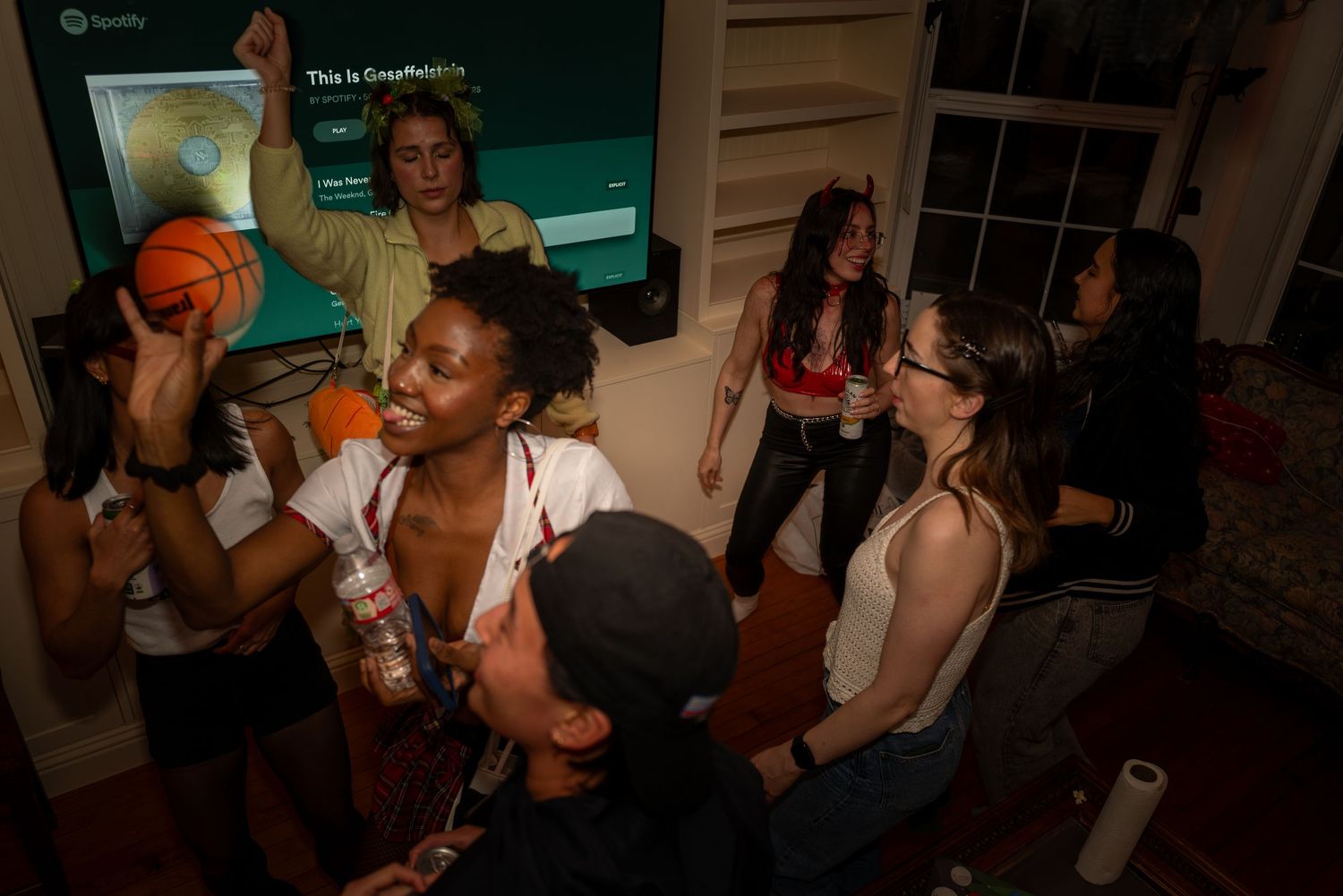 Diverse group of young women dancing and socializing at an indoor house party.