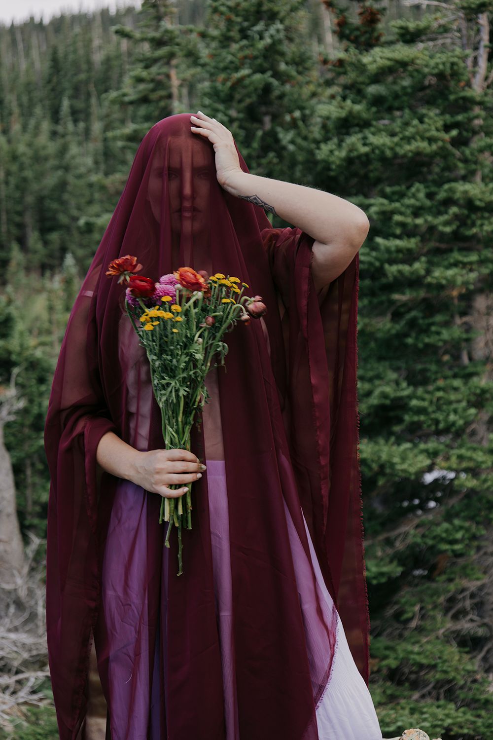 A series of images showing a figure in a burgundy veil holding a bouquet of red and yellow flowers in a forest setting.