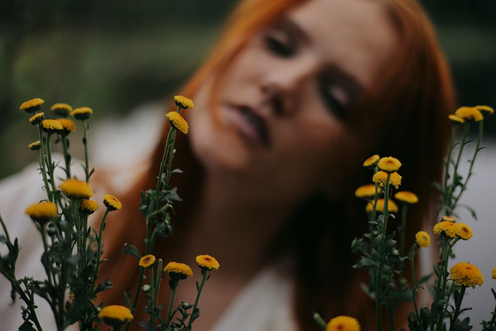 Artistic portrait with yellow tansy flowers in soft natural lighting creating a dreamy outdoor atmosphere.
