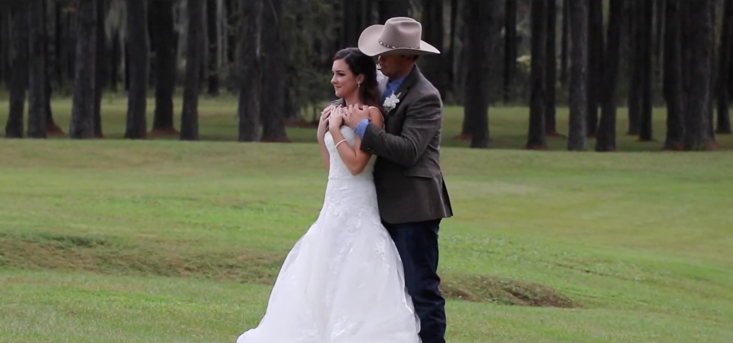 Wedding couple dancing on green golf course surrounded by pine trees.
