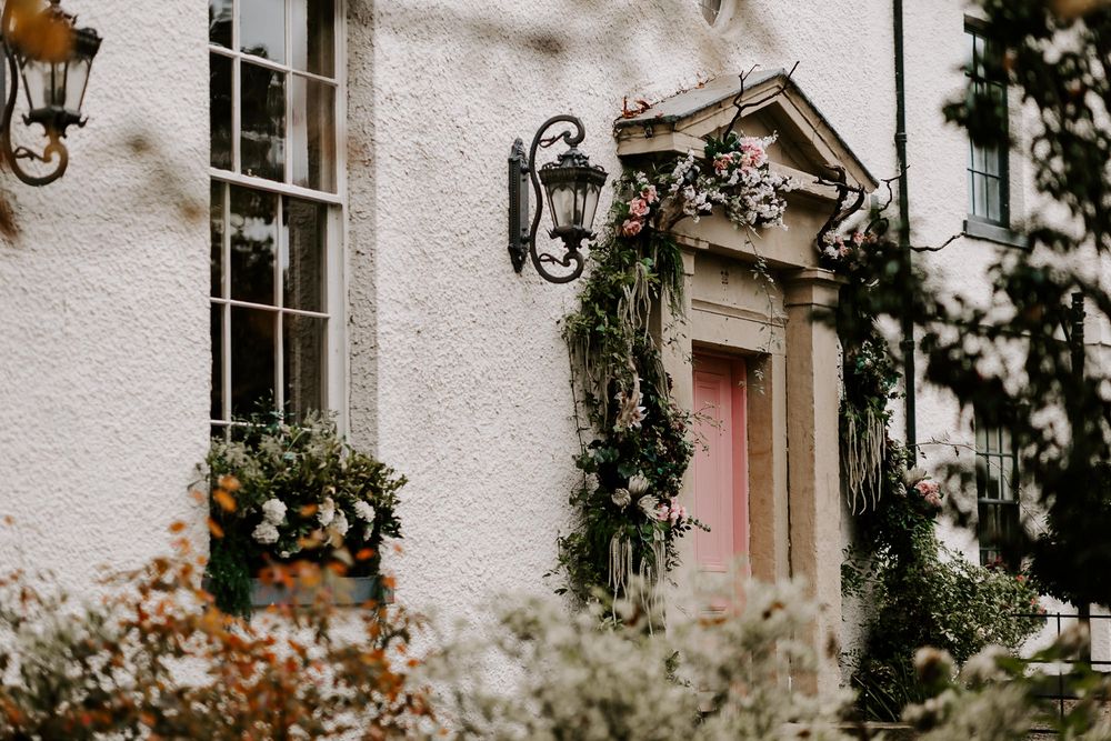 Elegant white stone house exterior with climbing vines and decorative wall sconces creates a romantic ambiance.