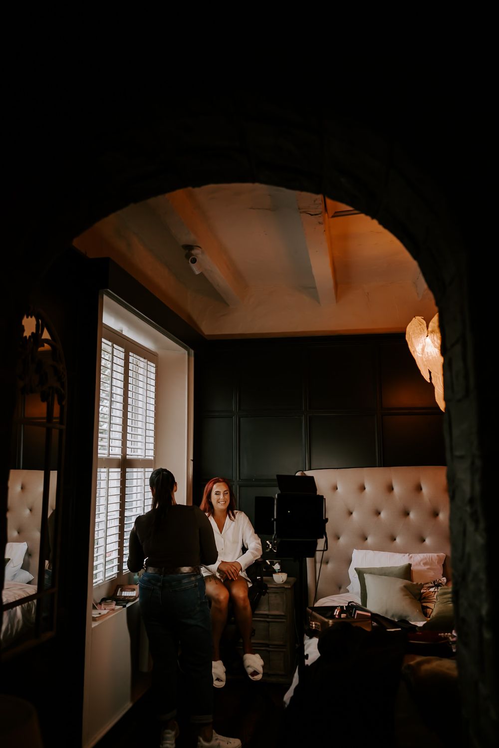A dimly lit room with people preparing for a wedding ceremony in a moody, intimate atmosphere.