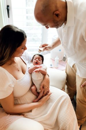 A healthcare provider examines a newborn baby being cradled by someone wearing a white dress.