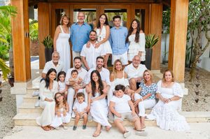 A group wearing coordinated white outfits sits together on stone steps for a casual outdoor family photo session.