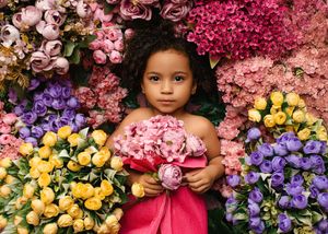 A colorful spring garden display features vibrant pink roses, yellow tulips, and purple irises in full bloom.