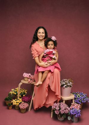 A series of professional studio portraits featuring matching pink dresses and floral arrangements against a burgundy backdrop.