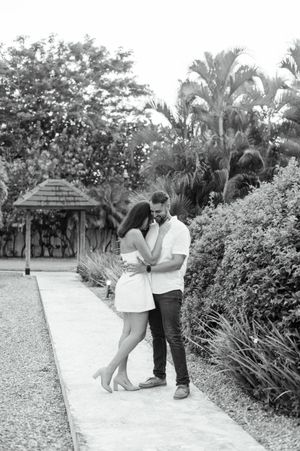 Black and white photo series of romantic couple sharing intimate moments in a tropical garden setting.