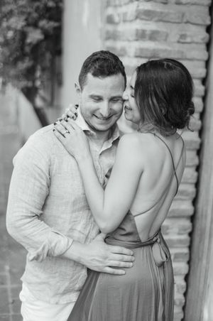 A couple shares an intimate moment in black and white as they embrace against a brick wall background.