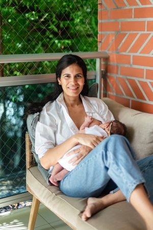 A person relaxes comfortably on a beige chair against a brick wall with greenery visible through windows.