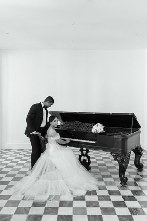 A couple in wedding attire playfully poses on a checkered floor in a series of black and white photos.
