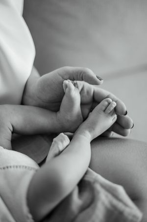 Black and white photo series showing close-up shots of a baby's tiny feet being gently held by adult hands.
