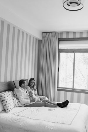 A series of black and white photos showing people relaxing on a cozy bed in a modern bedroom with striped wallpaper.