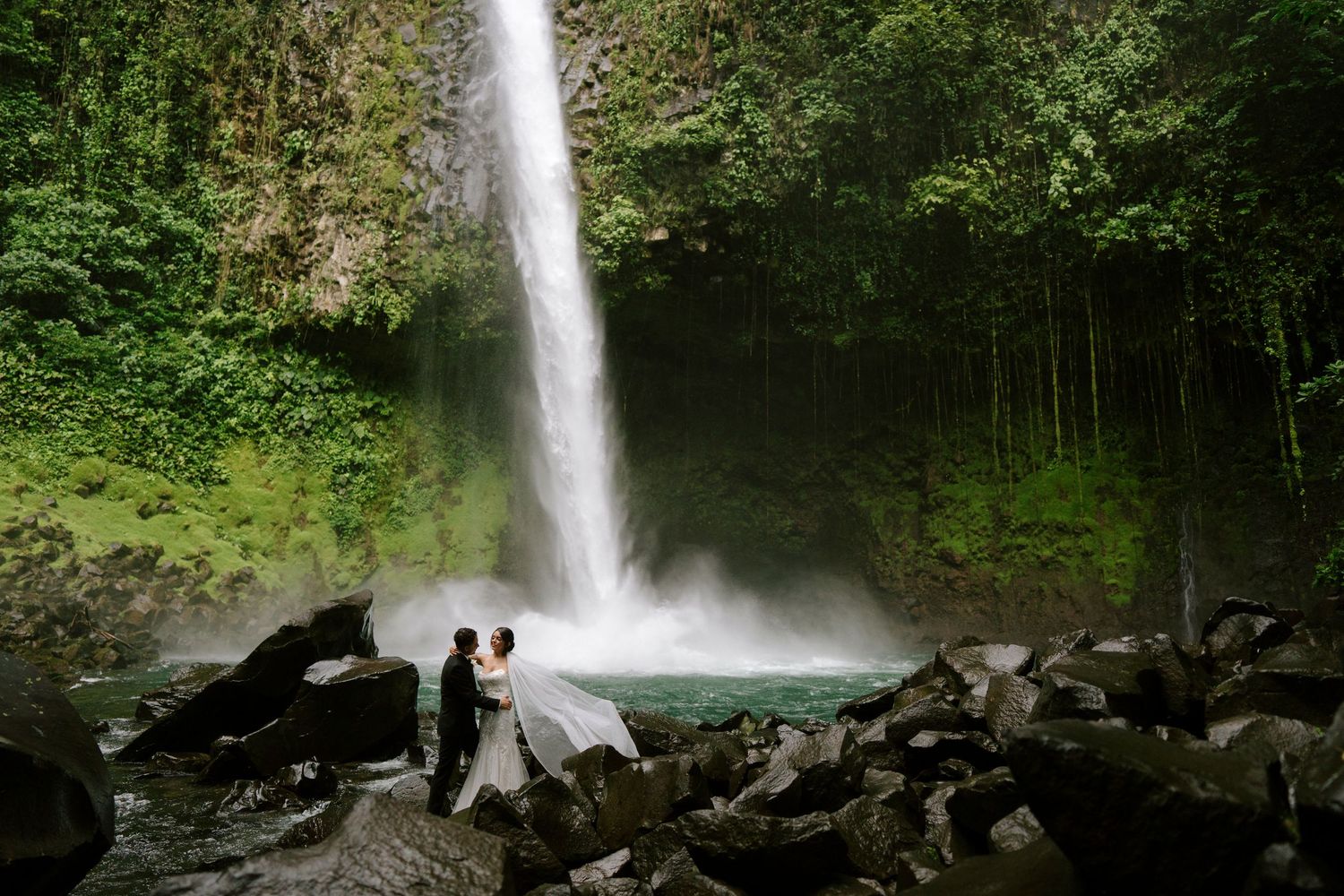Couple posing at La Fortuna Waterfall during an adventure elopement in Costa Rica.