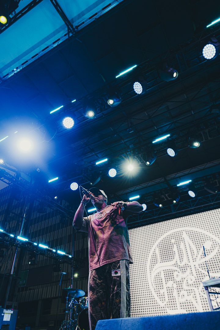 Performer on stage silhouetted against blue lighting and LED display backdrop during live show.
