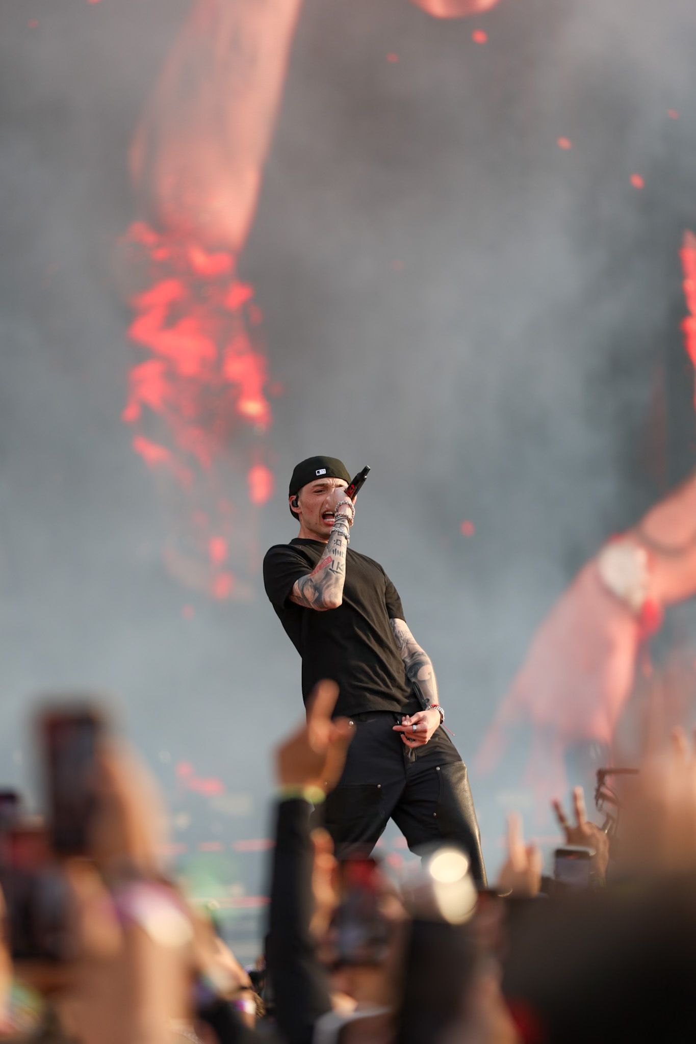 Performer on stage silhouetted against dramatic red lighting and smoke effects during a concert performance.