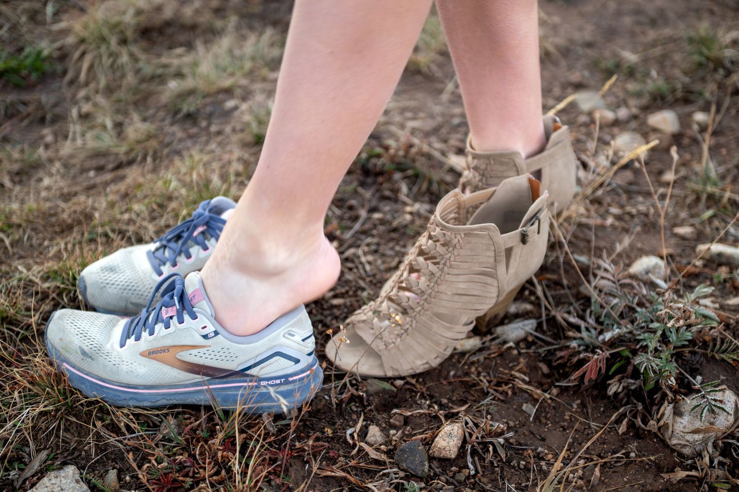 A closeup of bride changing from her high heel shoes back into her tennis shoes. She is squatting down and unzipping the back of her heels.