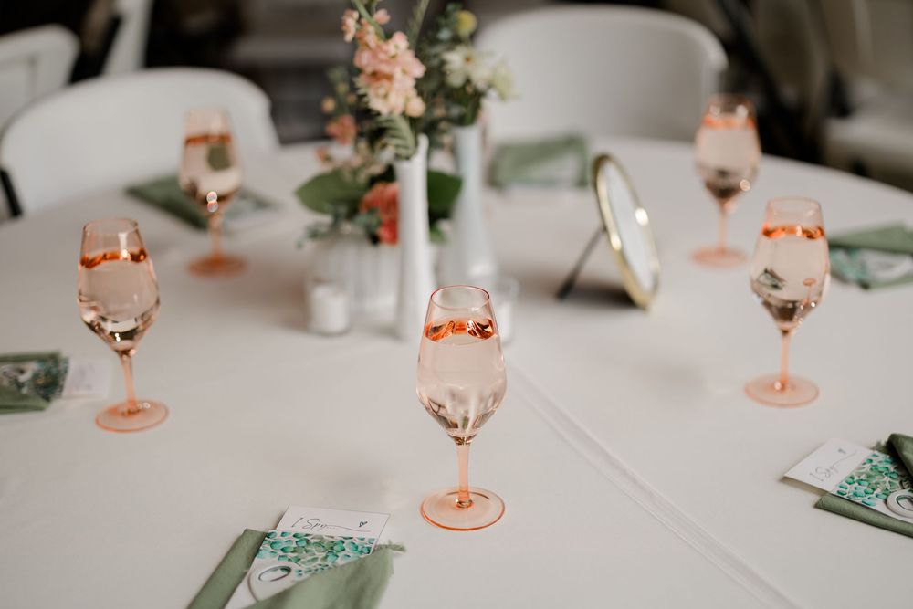 Elegant table setting with pink depression glass goblets and delicate floral centerpieces at a wedding reception.