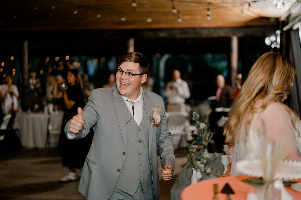 Wedding guests dance and celebrate on a dimly lit dance floor during an evening reception celebration.
