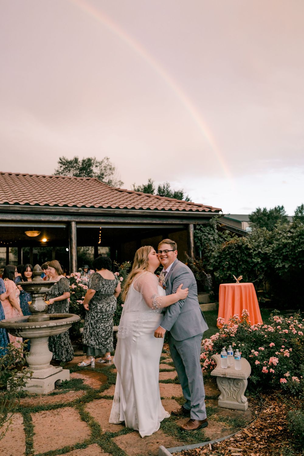 Couples dancing together at an outdoor garden reception with terracotta tiles and decorative urns at sunset.