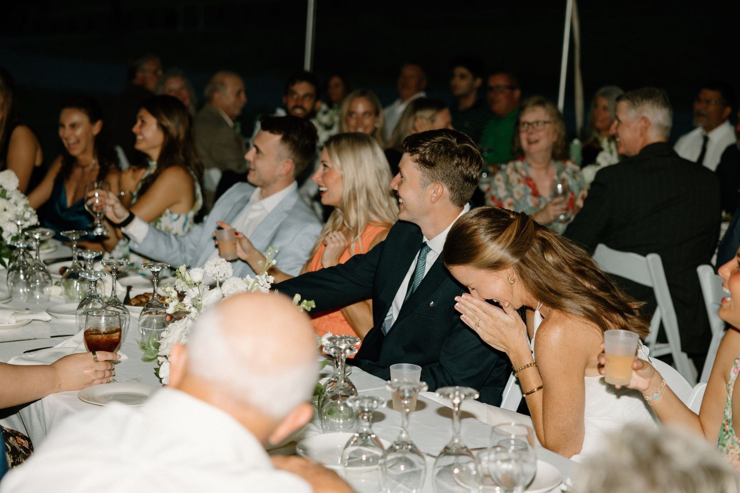Wedding reception guests seated at elegant dining tables during an evening celebration.