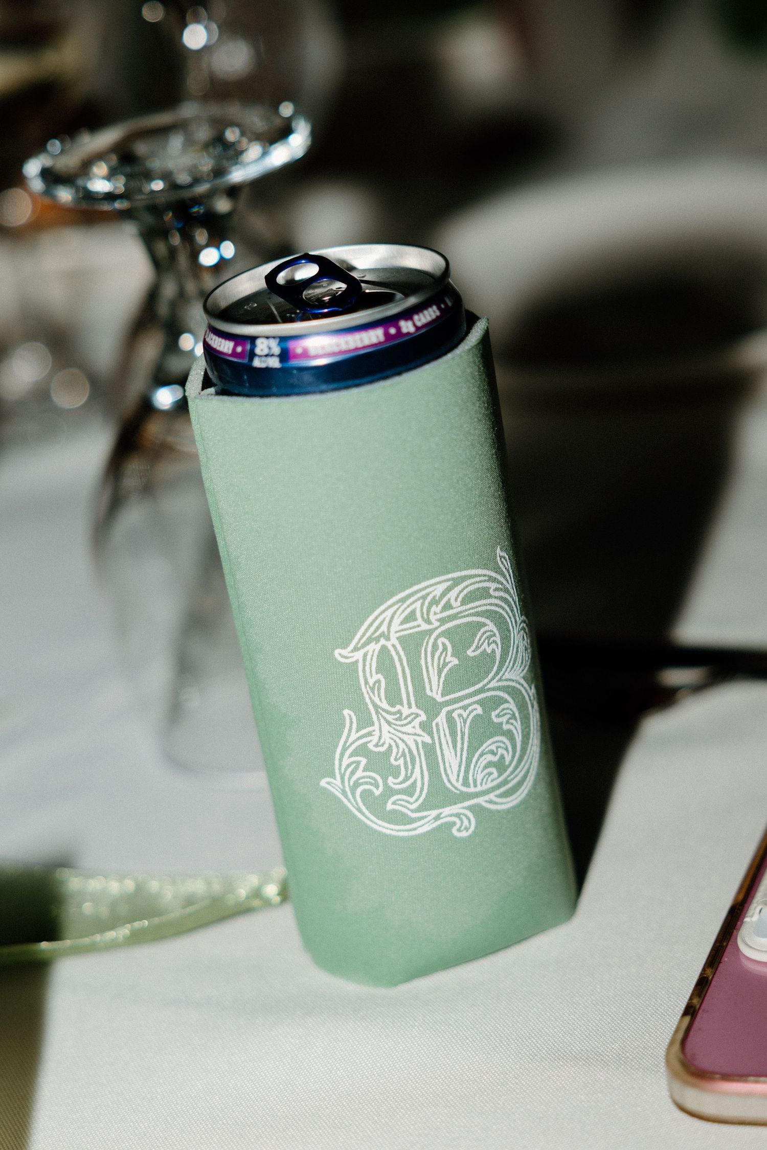 Mint green foam beverage koozies with white decorative designs displayed in sequence on a white surface.
