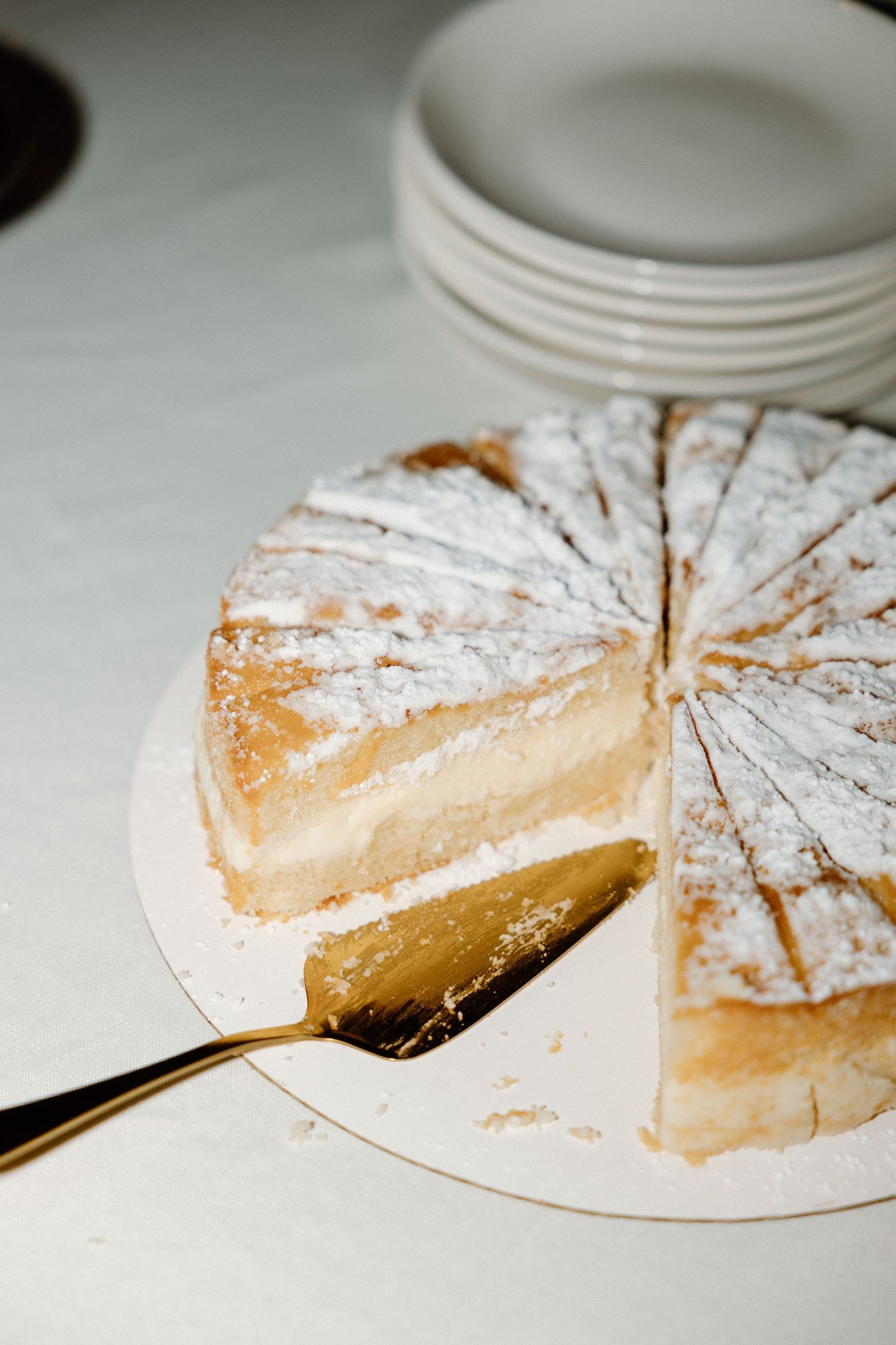 Sliced vanilla custard tart with powdered sugar dusting shown from multiple angles on white plates.
