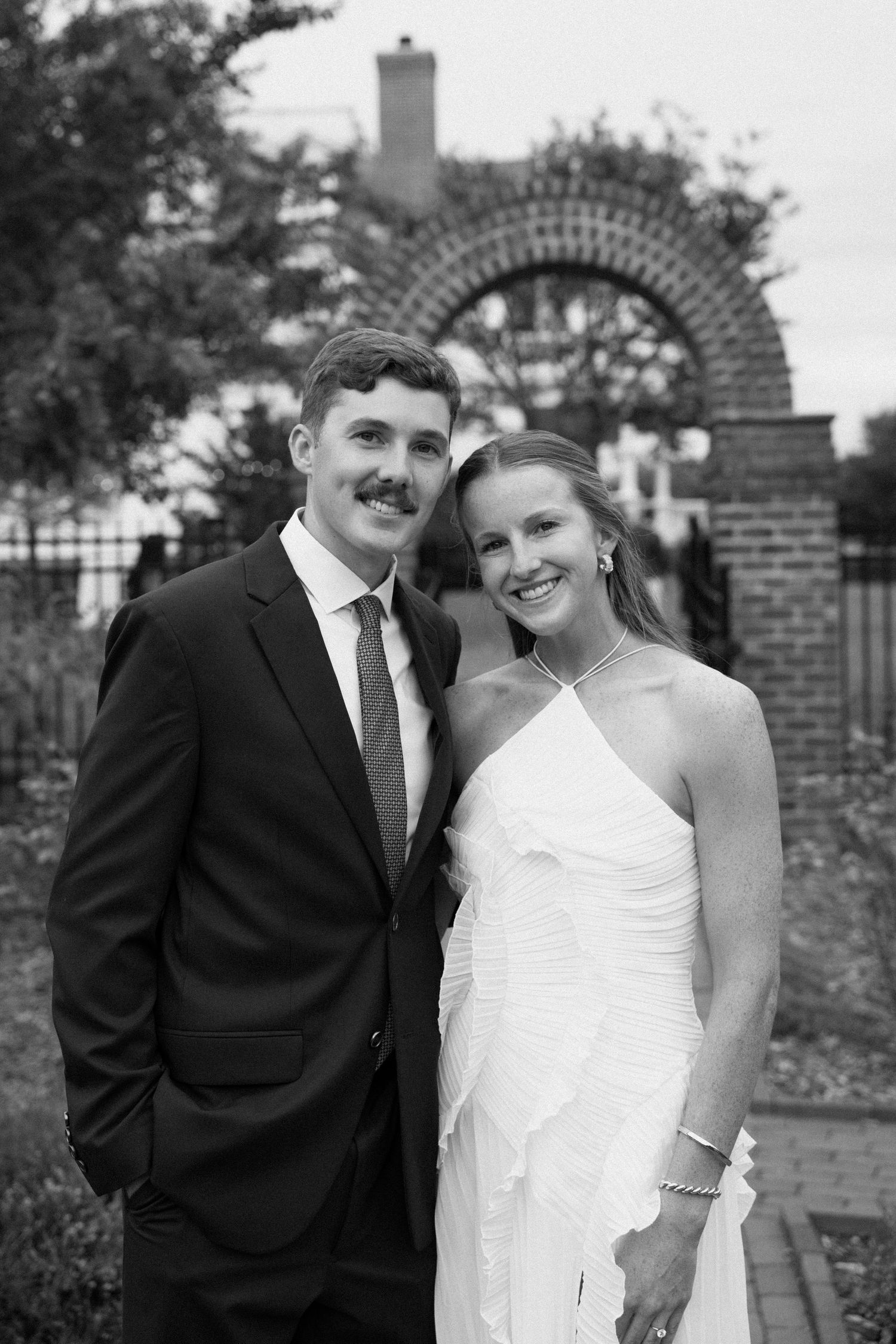 Black and white wedding photos showing a couple in formal attire posing together in an outdoor garden setting.