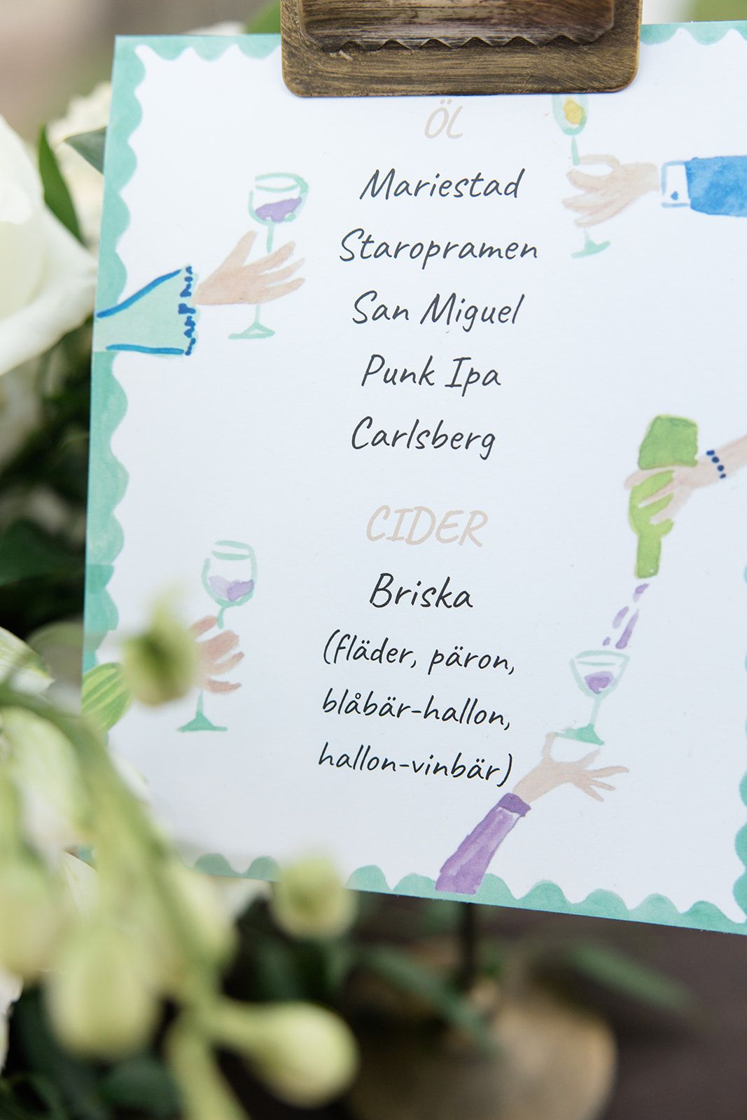 Handwritten menu cards showing beer and cider names including Mariested, San Miguel, and Carlsberg against a blurred background.