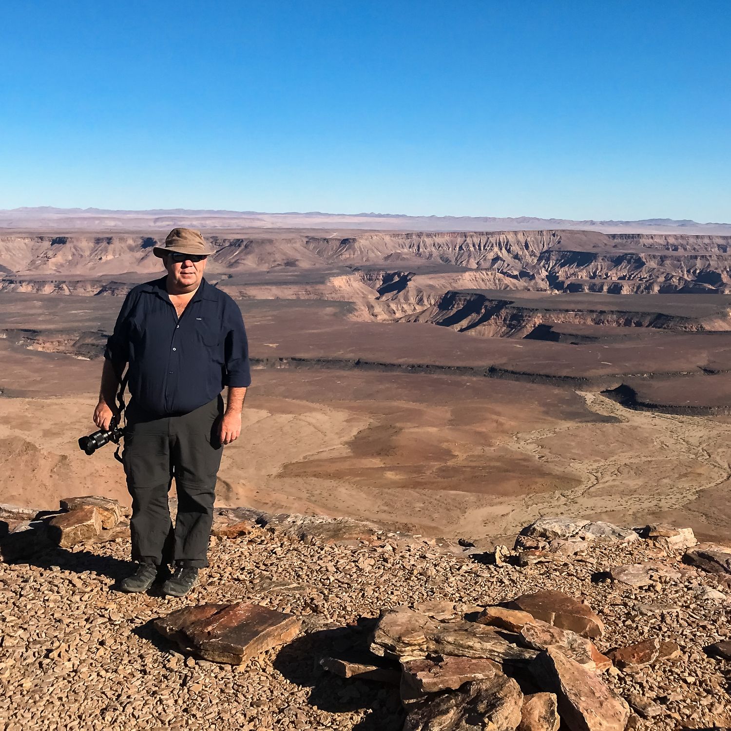 Panoramic view of desert canyons and rock formations in the American Southwest with person overlooking vast landscape.